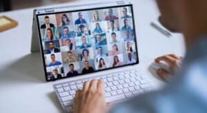 POV of person on cloud video conferencing meeting showing monitor with many participants.